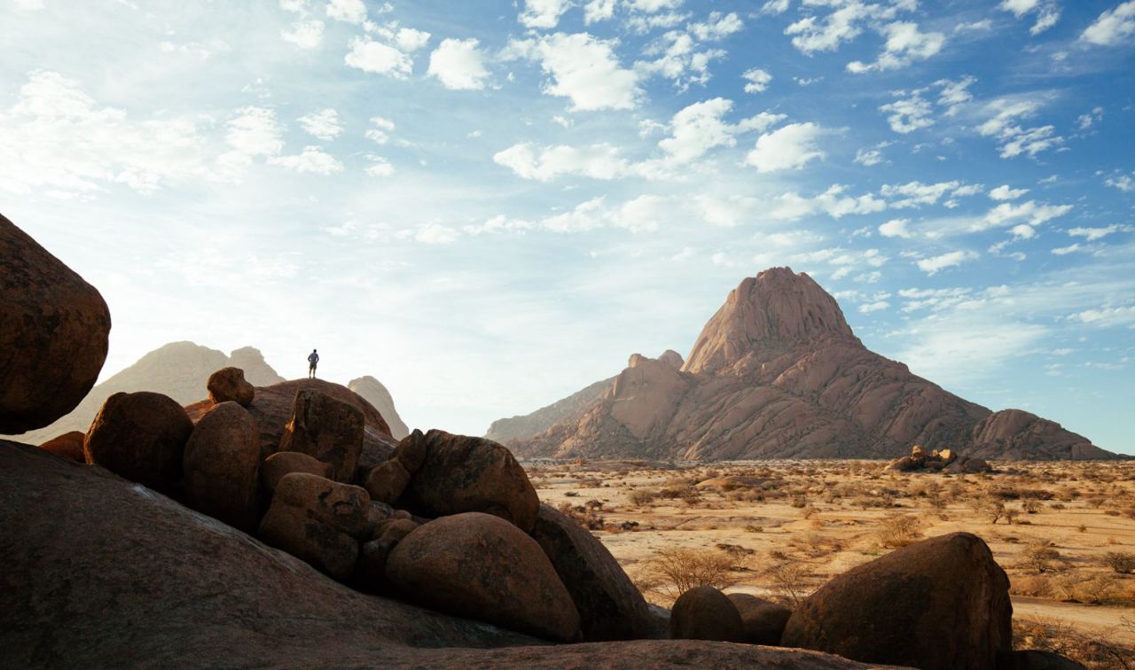 Die Spitzkoppe in Namibia, mit Felsen und einem Wanderer im Vordergrund